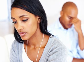 Woman with her back towards a man with his head in his hand.