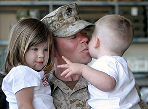 Man in military fatiques holding a little boy and a little girl.