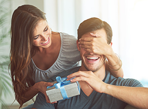 Woman covering a man's eyes with her hand.