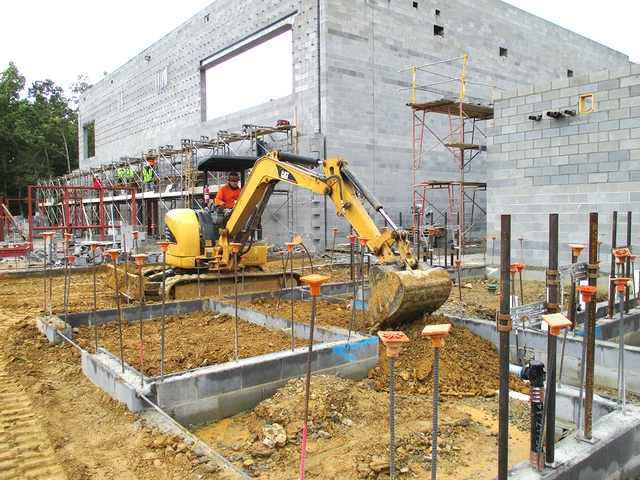 Excavator caterpillar around brick building 